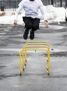 Athlete jumping over yellow hurdles in an icy parking lot after a snow storm