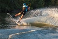 An athlete jumps over the water. Wakeboard park at sunset. Rider performs a trick on the board