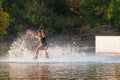 An athlete jumps over the water. Wakeboard park at sunset. Rider performs a trick on the board