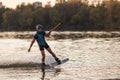 An athlete jumps over the water. Wakeboard park at sunset. Rider performs a trick on the board