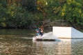 An athlete jumps over the water. Wakeboard park at sunset. Rider performs a trick on the board