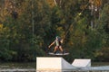 An athlete jumps over the water. Wakeboard park at sunset. Rider performs a trick on the board