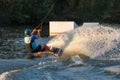 An athlete jumps over the water. Wakeboard park at sunset. Rider performs a trick on the board