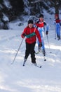 Athlete in kids ski cross-country running winter competition in snow covered landscape
