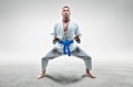 Athlete in a kimono with a blue belt stands in a fighting position. Concept of karate, sambo, jujitsu Royalty Free Stock Photo