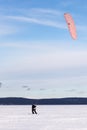 Athlete kite surfer on skis at winter training on Lake Onega on a sunny day.