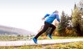 Athlete at the lake running against colorful autumn nature.