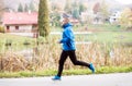 Athlete at the lake running against colorful autumn nature