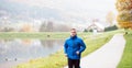 Athlete at the lake running against colorful autumn nature