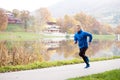 Athlete at the lake running against colorful autumn nature