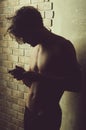 Athlete macho with naked torso in trunks using mobile phone