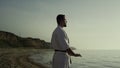 Athlete making meditation exercise on beach. Karate fighter perfecting technique