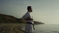 Athlete making meditation exercise on beach. Karate fighter perfecting technique