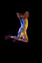 Athlete man, basketball player, in motion of powerful basketball shot against black studio background in mixed neon Royalty Free Stock Photo