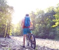 Athlete man crossing mountain river with bicycle