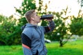 Athlete man is drinking water protein. A bodybuilder listens to music while training. In the summer in the park in the Royalty Free Stock Photo