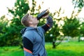 Athlete man is drinking water protein. A bodybuilder listens to music while training. In the summer in the park in the Royalty Free Stock Photo
