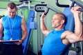 Athlete man in gym with personal fitness trainer