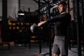 Concentrated muscular man in sportswear doing exercises with kettlebell while standing in cross-fit gym. Royalty Free Stock Photo