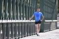 Athlete man stretching legs warming up calf muscles before running workout leaning on railing city urban park Royalty Free Stock Photo