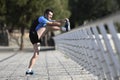 Athlete man stretching legs warming up calf muscles before running workout leaning on railing city urban park Royalty Free Stock Photo