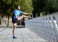 Athlete man stretching legs warming up calf muscles before running workout leaning on railing city urban park Royalty Free Stock Photo