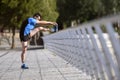 Athlete man stretching legs warming up calf muscles before running workout leaning on railing city urban park Royalty Free Stock Photo