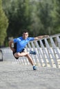 Athlete man stretching legs warming up muscles before running workout leaning on railing city urban park Royalty Free Stock Photo