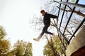 Athlete man, young guy jumps over parking lot, practice Parkour in public park among over sky view. Eye fish filter. Royalty Free Stock Photo