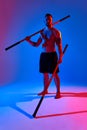 athlete men silhouette with stick training karate using sports tool in studio on colorfull lights background