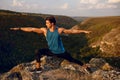 Athlete, fit, young man doing stretching exercises, workout outside on forest, mountain background. Summer landscape.