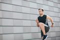 Athlete played sport in city. Man raises legs high, running near gray wall