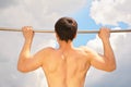 Athlete pull oneself up on sky background