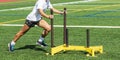 Athlete pushing yellow sled on green turf field