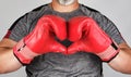 athlete in red boxing leather gloves shows hands with a heart symbol