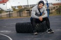 An athlete rests on a tire after training on a sports field. Sports lifestyle.