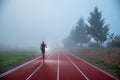 Athlete at the Running track with red lines over misty blue sky. Sport photo, edit space