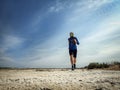 Athlete runs trailrunning on a dry deserted seashore