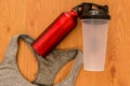 Athlete`s bottle of water and a red thermocafe with a gray sport braa on wooden background Royalty Free Stock Photo