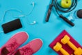 Athlete`s set with female clothing, dumbbells and bottle of water on bright blue background