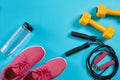 Athlete`s set with female clothing, dumbbells and bottle of water on bright blue background