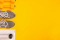 Athlete`s set with female clothing, dumbbells and bottle of water on yellow background