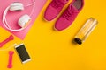 Athlete`s set with female clothing, dumbbells and bottle of water on yellow background