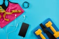 Athlete`s set with female clothing, dumbbells and smart on bright blue background