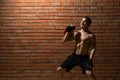 An athlete shows how to do an exercise with the weight to form a muscle in the fitness room on a red wall background