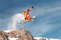 An athlete skier is jumping from high rock high in the mountains.