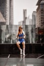 Athlete slim blonde fitness woman trainer runner in blue sportswear is sitting taking rest on form on city street