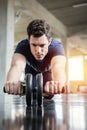 Athlete sporty man doing exercise with abs roller wheel to strengthen his abdominal muscle in gym