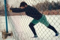 Athlete stretching calves on the fence on a snowy day