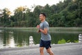 An athlete, strong Asian male runner in sportswear is running in a parl in the morning